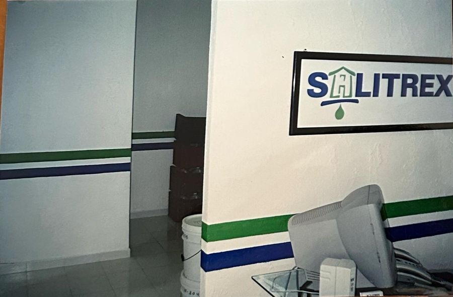 Oficina de Salitrex con el logo en la pared y franjas azul y verde